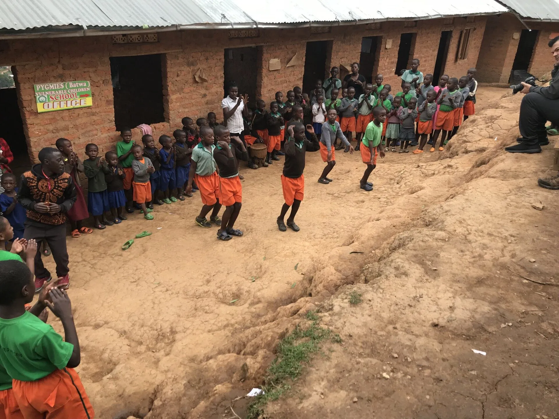 Children performing a traditional dance outside their school